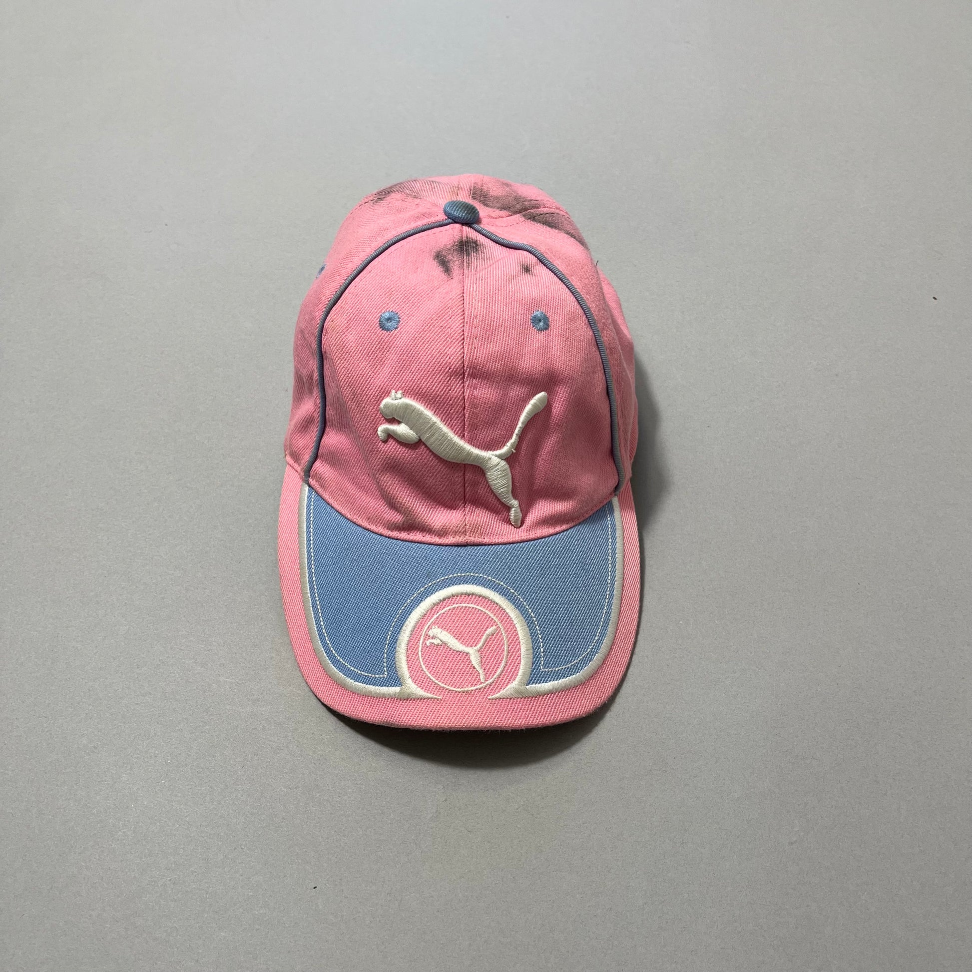 Pink and blue cap with Puma logo on a gray background.