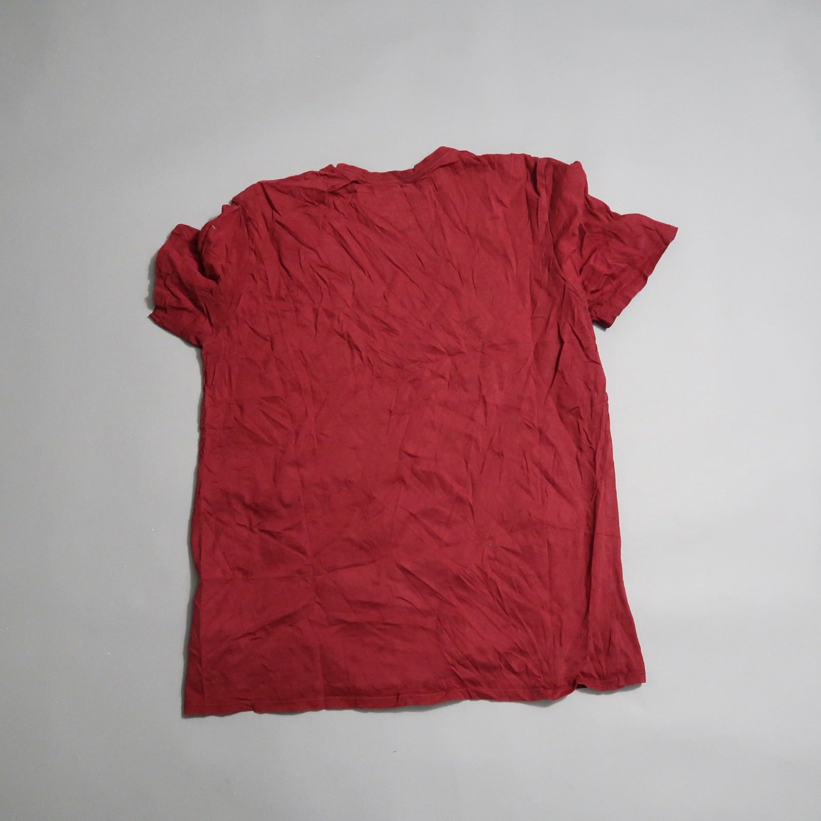 Wrinkled red T-shirt lying on a flat surface.