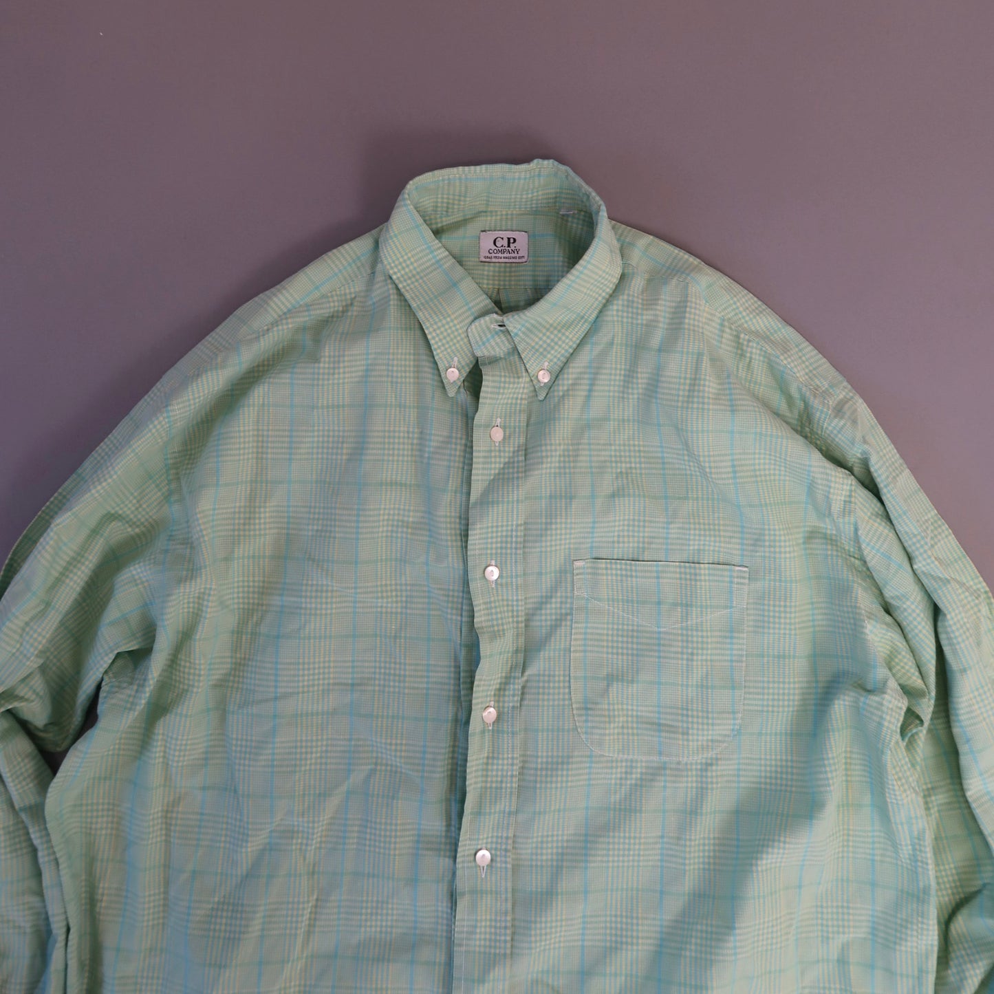 Light green plaid button-up shirt on a gray background.