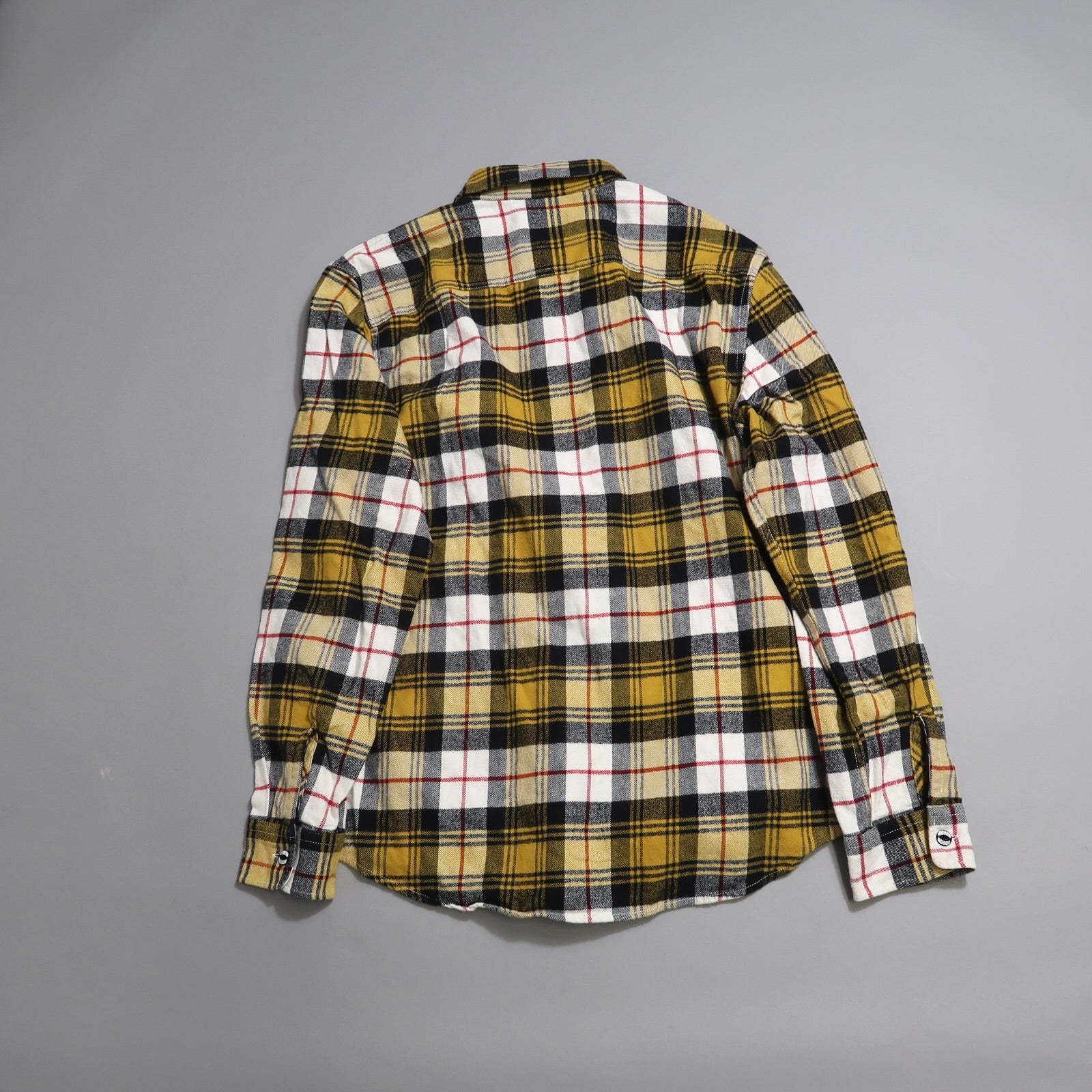 Yellow plaid flannel shirt on a gray background, facing backward.