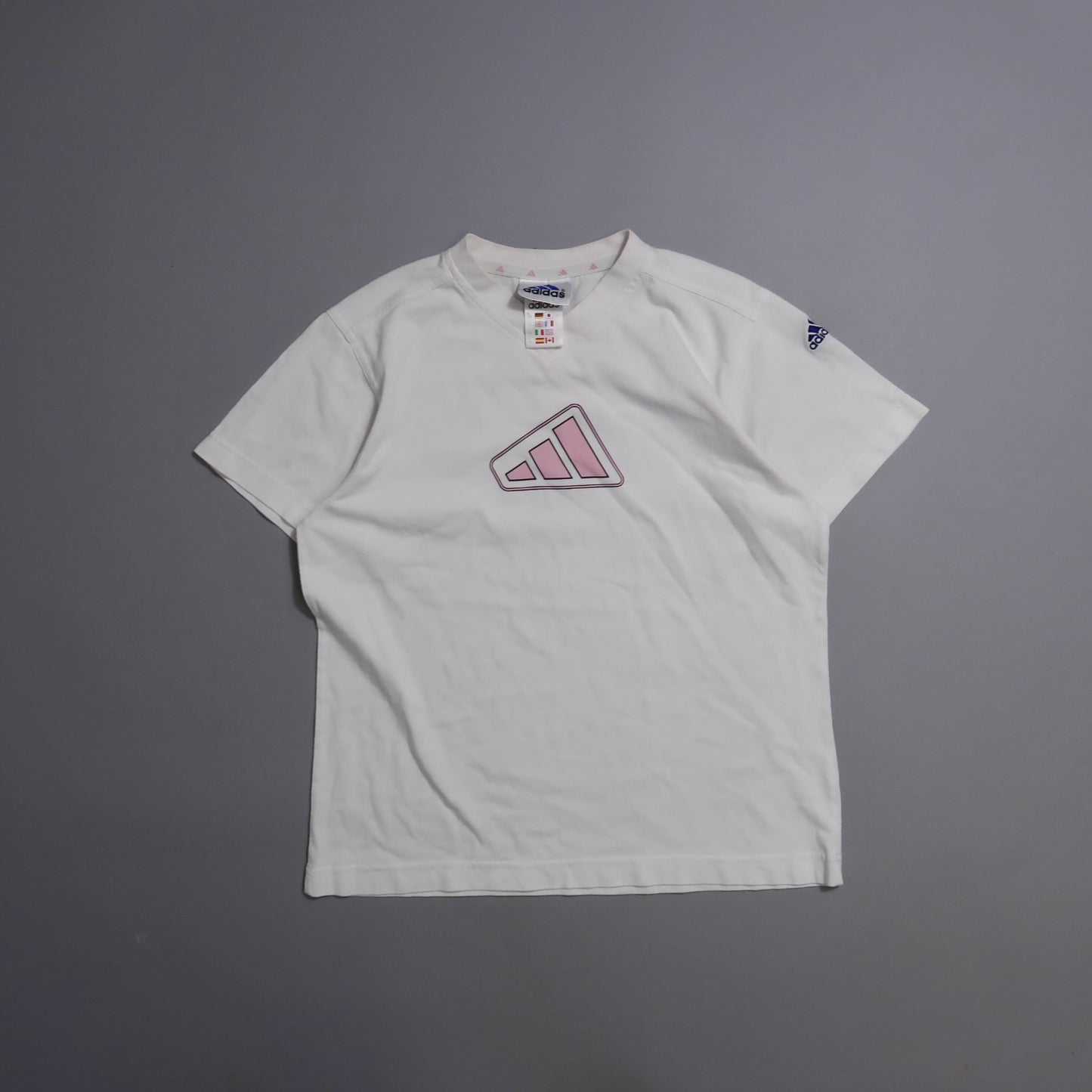 White T-shirt with pink logo on front, gray background.