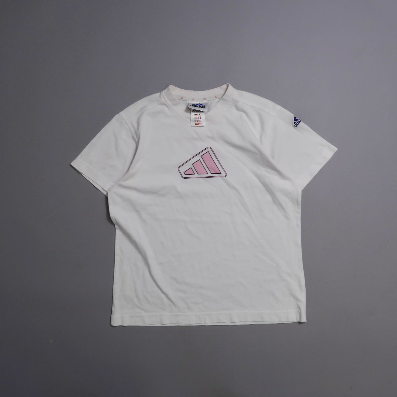 White T-shirt with pink logo on front, gray background.