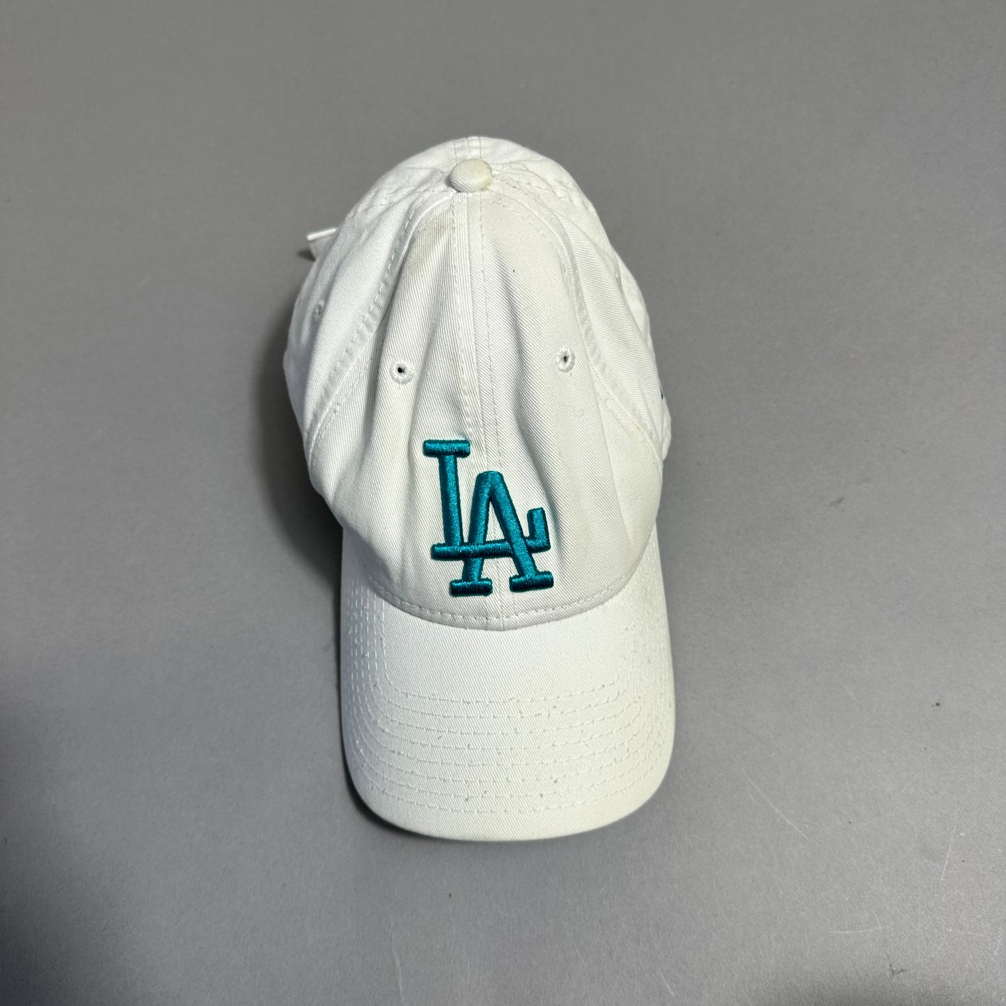 White cap with teal nullLAnull logo on a gray background.