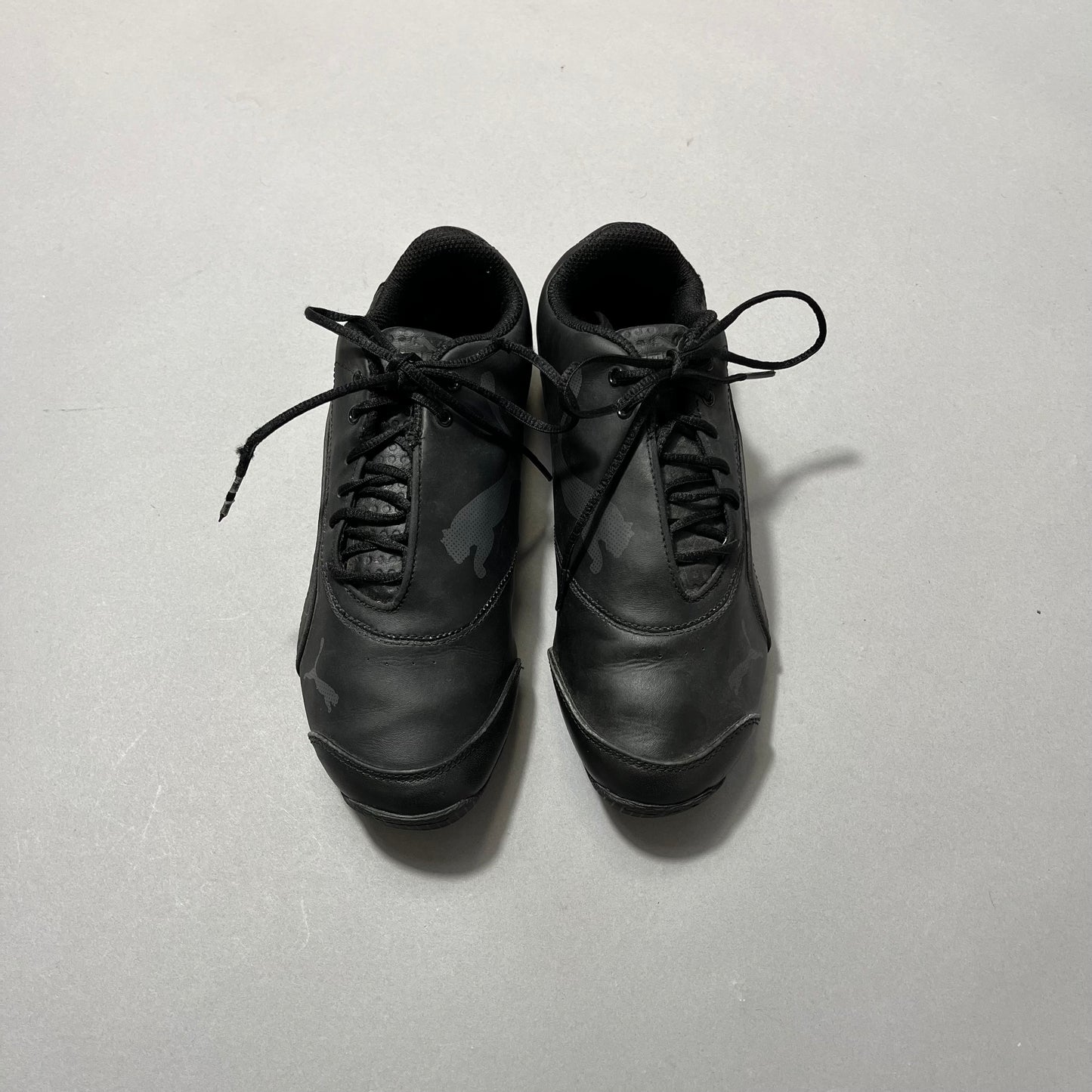 Black athletic shoes with laces on a plain background.
