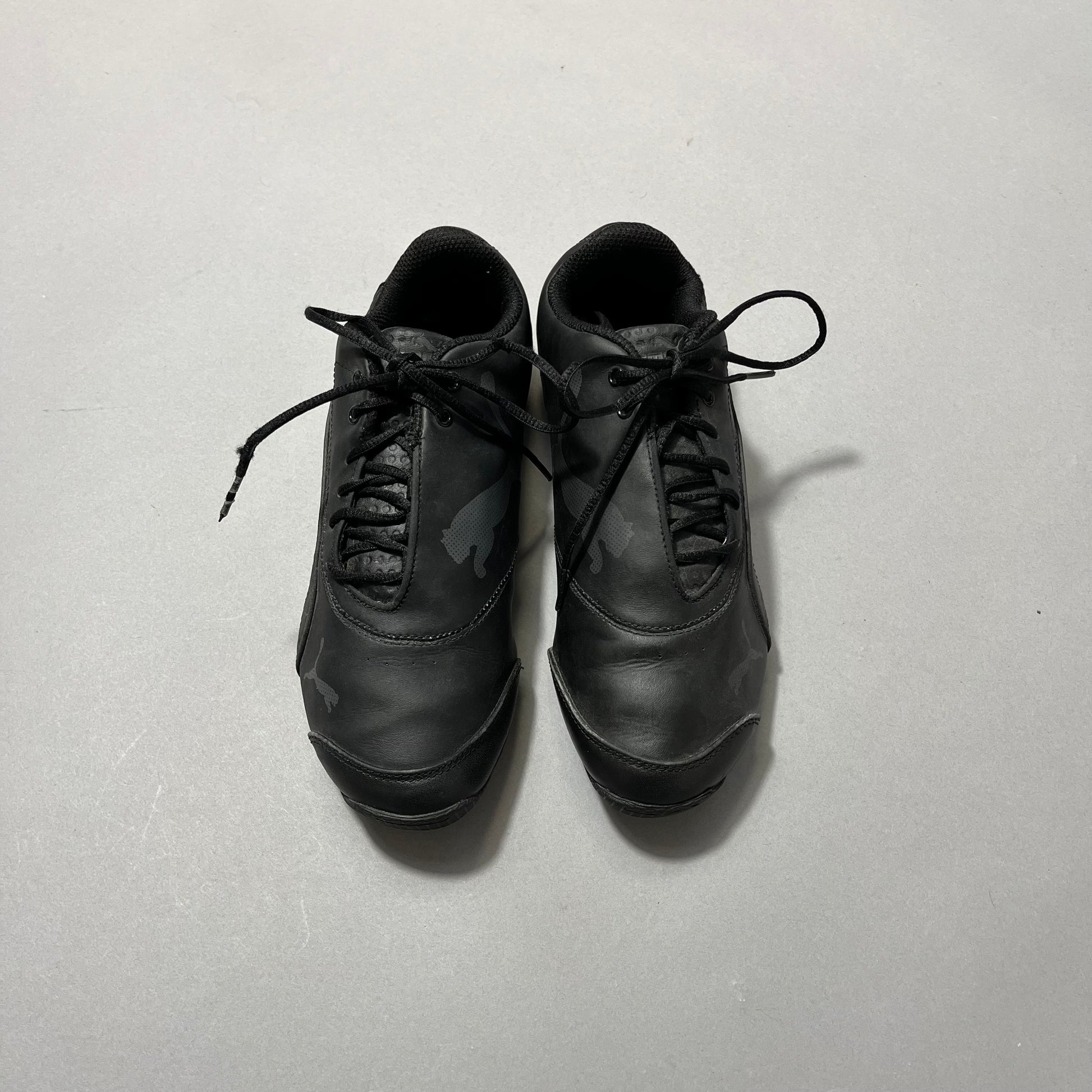 Black athletic shoes with laces on a plain background.