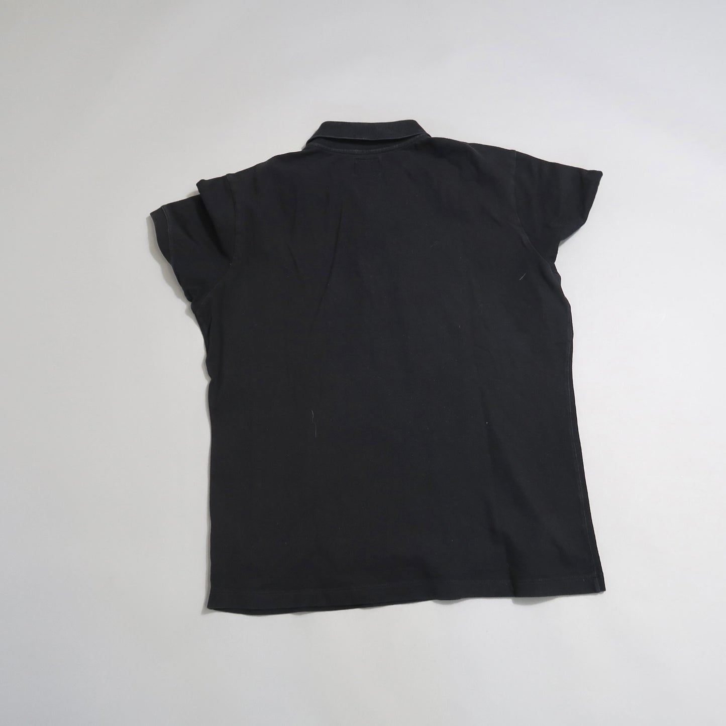 Back view of a plain black T-shirt on a light background.