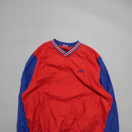 Red and blue long-sleeve V-neck sports jacket on a gray background.