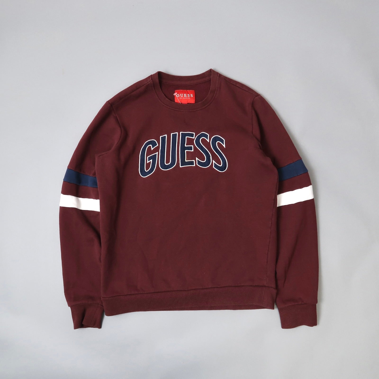 Maroon sweatshirt with nullGUESSnull text and striped sleeves.