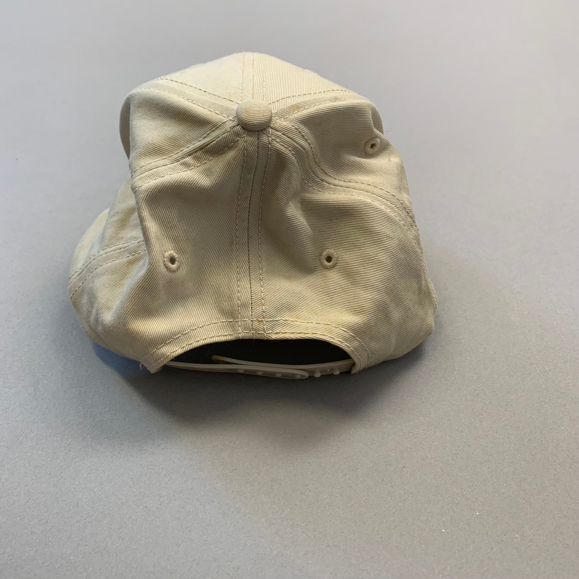 Beige baseball cap upside down on a gray surface.