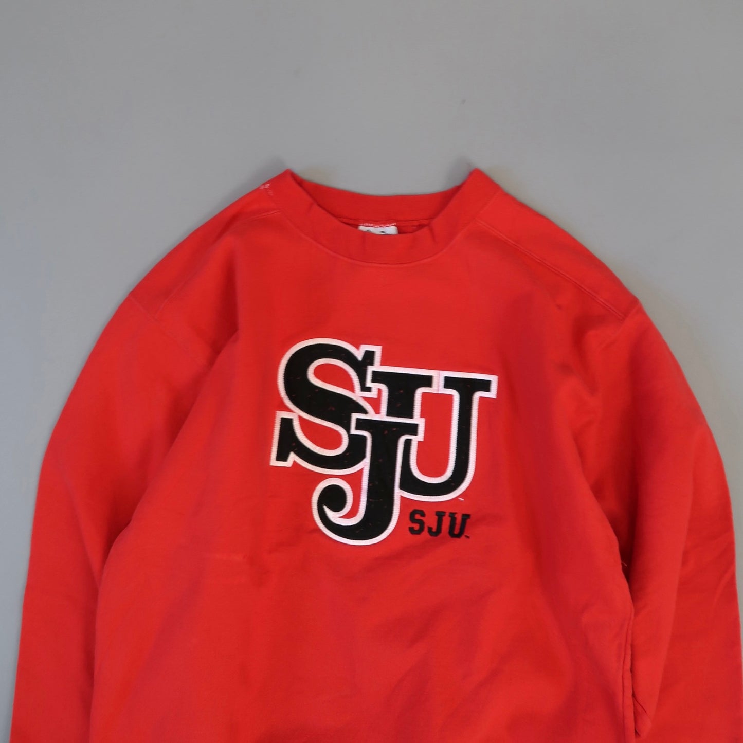Red sweatshirt with nullSJUnull logo in black and white letters.