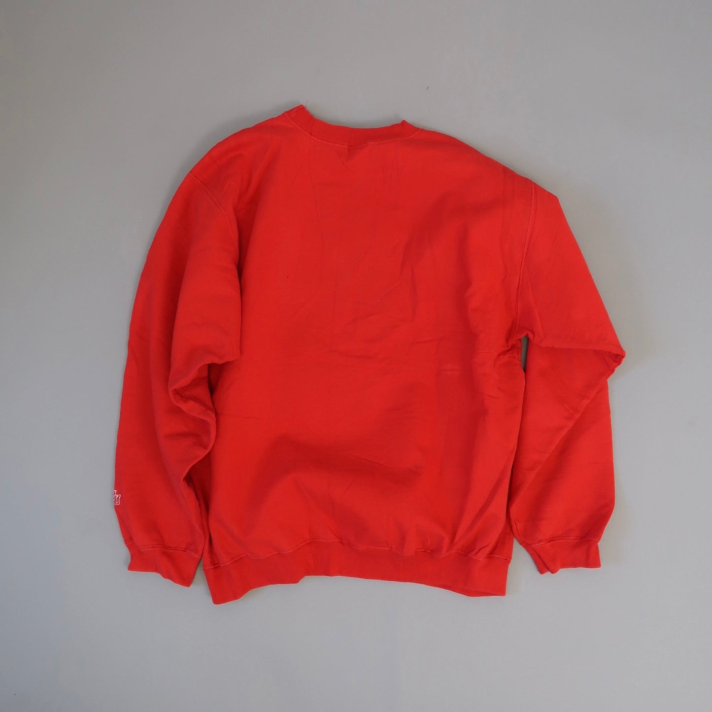 Red crewneck sweatshirt laid flat on a light gray background.